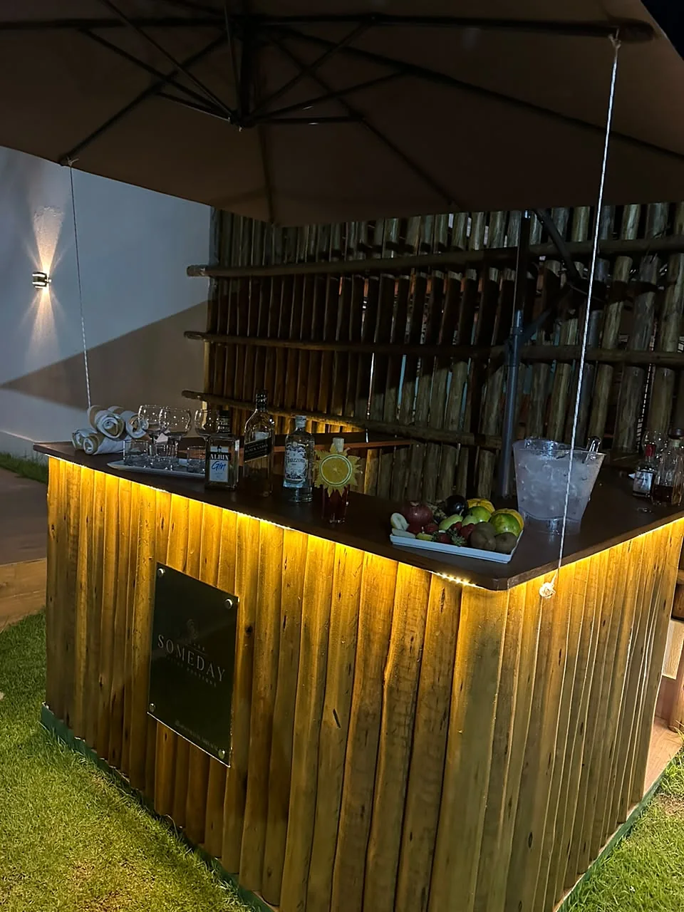 Bar de bambu iluminado à noite, com frutas e garrafas