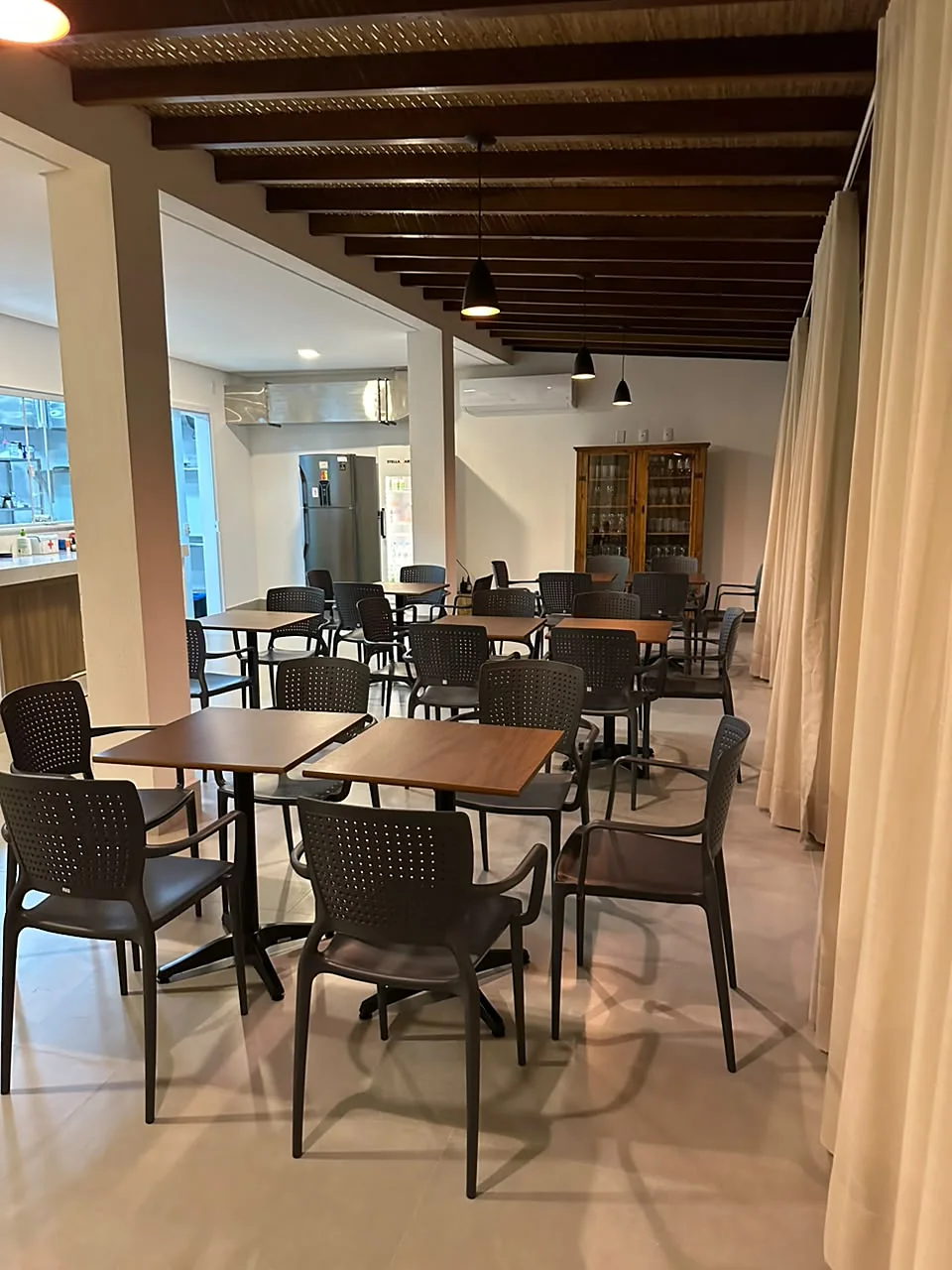 Salão do café da manhã com vigas de madeira e cortinas de linho