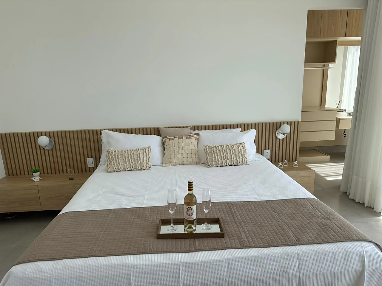 Suíte Master: cama de casal com bandeja de vinho e cabeceira de madeira ripada