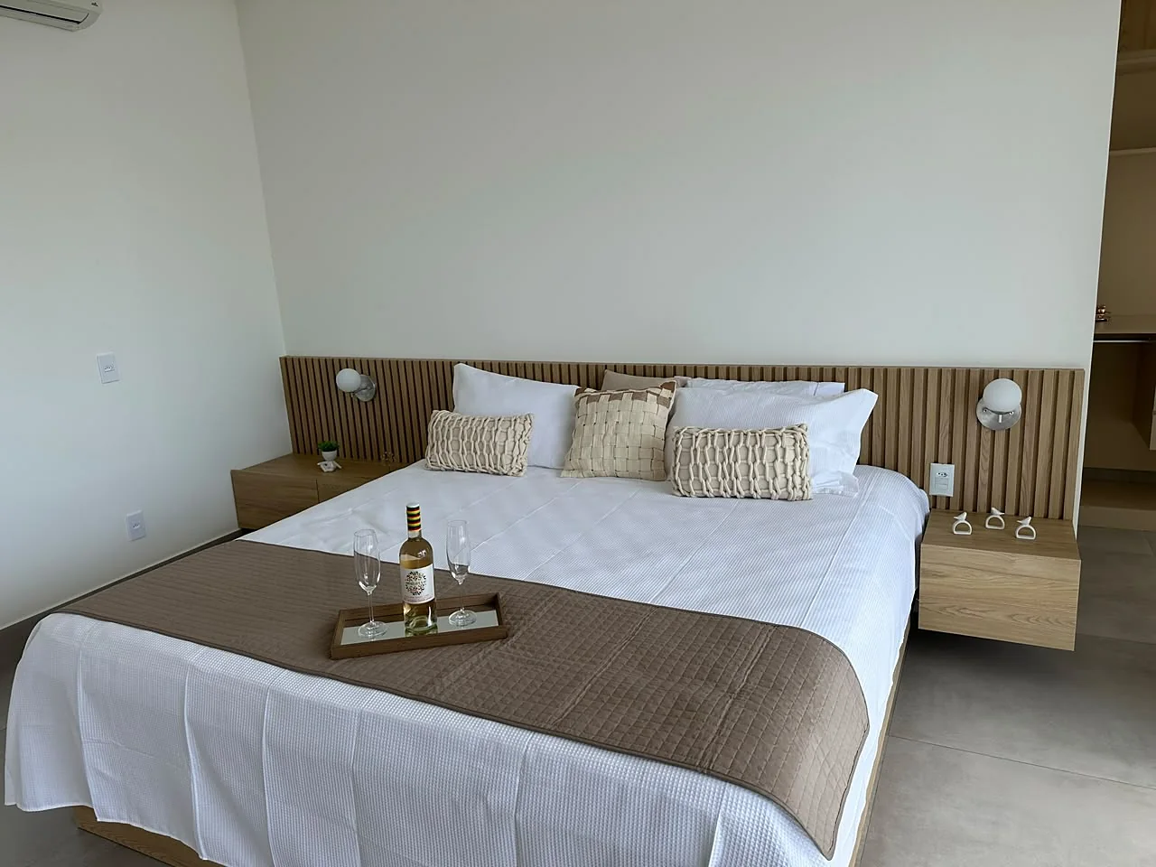 Suíte Master com cama de casal, arandelas e bandeja de vinho