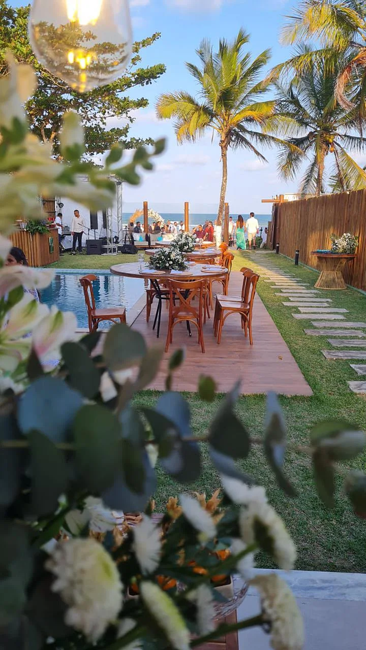 Jardim florido com mesas e a praia ao fundo