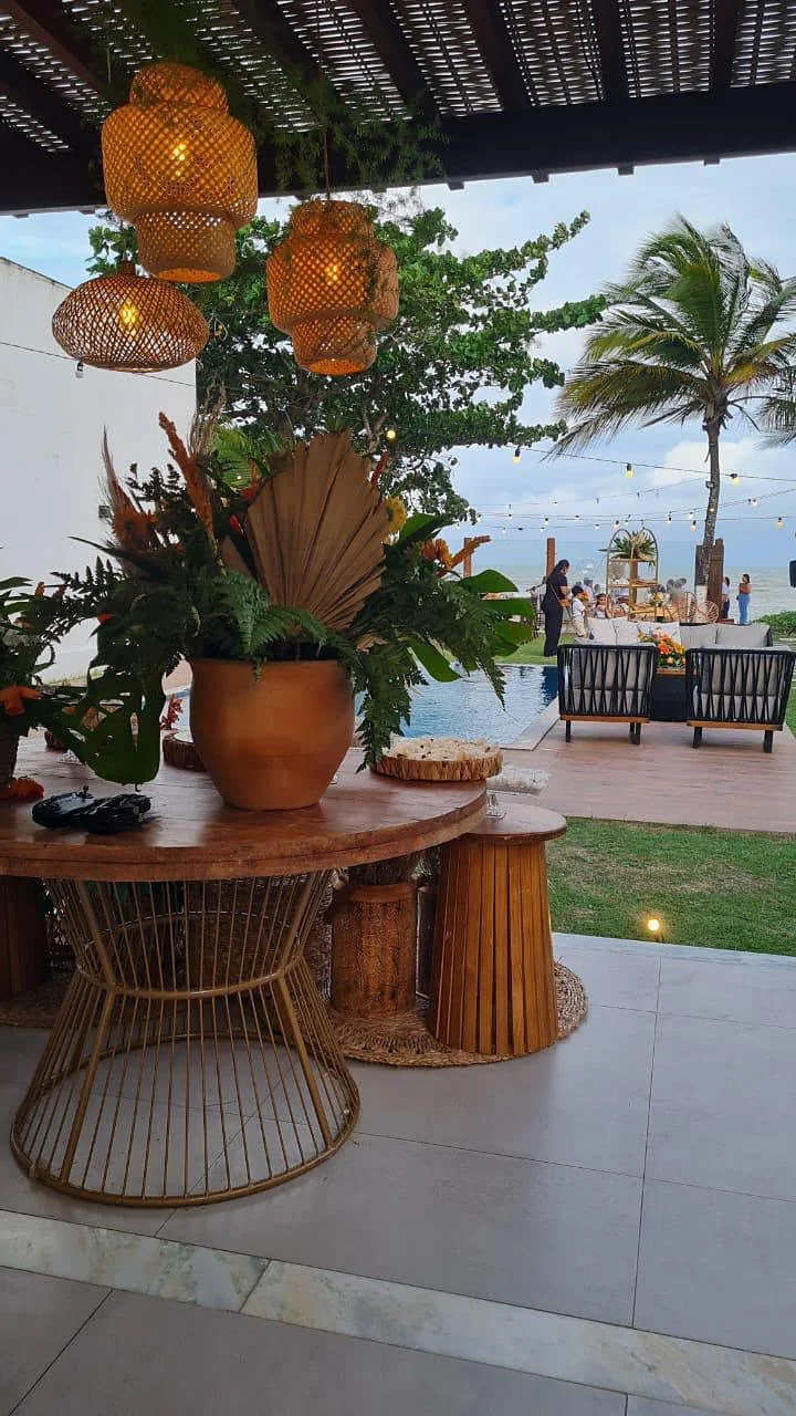 Mesa redonda decorada com folhagens e flores sob o pergolado