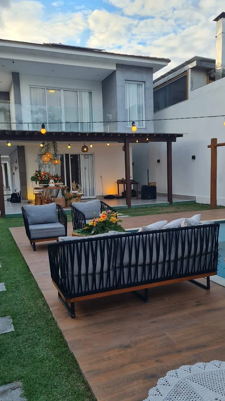 Casa, deck de madeira e sofá ao lado da piscina, durante o dia